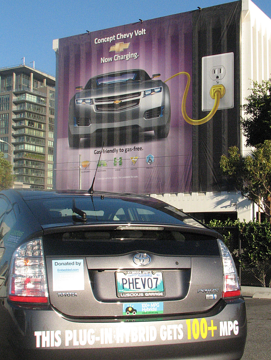 CalCars' Prius converted at LA Auto Show November 2007 in front of an ad for GM's Chevy Volt PHEV.